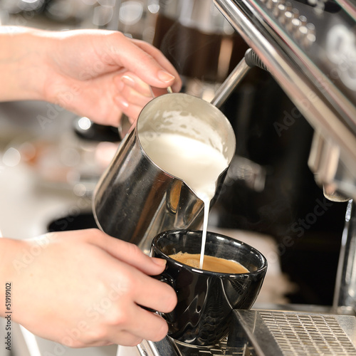 Obraz w ramie Waitress hands pouring milk making cappuccino
