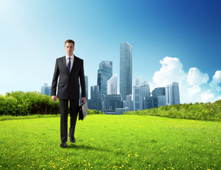 Wall Mural - business man walking on green field and modern city