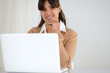 © pablocalvog - Smiling woman looking at you and using her laptop