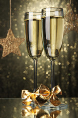 Two glasses of champagne on bright background with lights