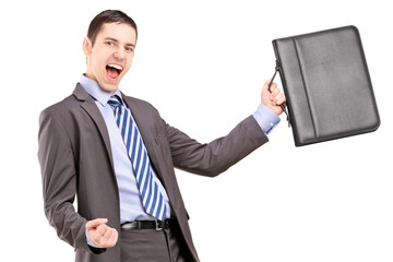 Wall Mural - A happy young businessman holding a briefcase and gesturing happ