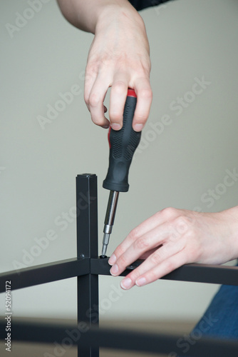 Fotografie, Tablou Vertical of hands screw together a piece of furniture, no body