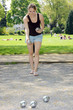 Junge Frau spielt Boule im Park
