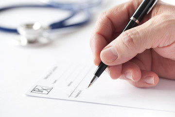 Doctor writing a prescription on Rx form in the consulting room