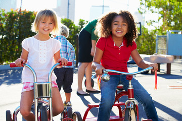 Wall Mural - Two Girls Riding Tricycles In Playground