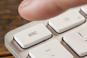 Finger Pressing Escape on a Grey Computer Keyboard