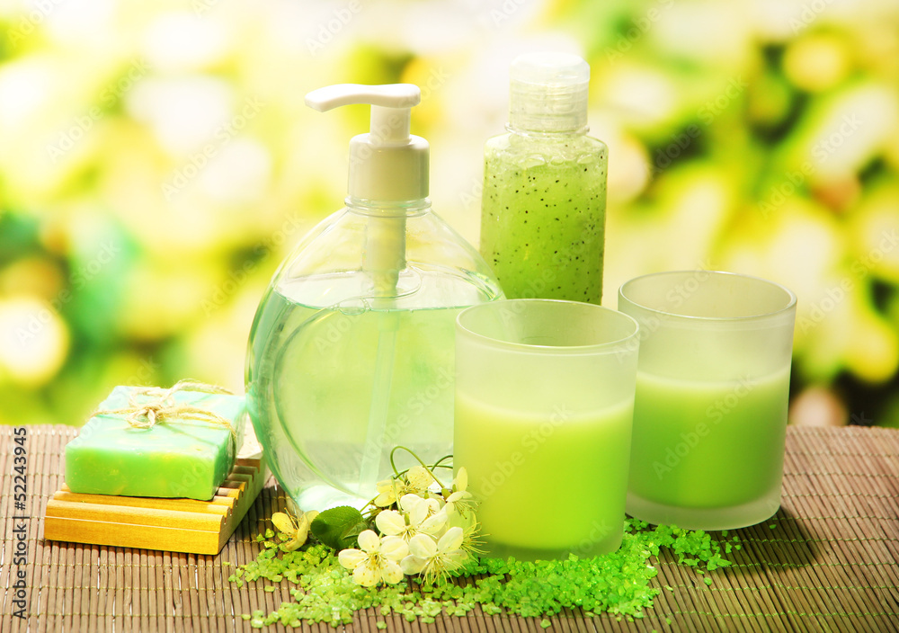 Cosmetics bottles and natural handmade soap on green background