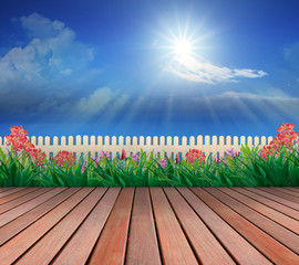 wood terrace and flowers garden with blue sky and sunshine above