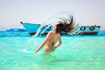 Young brunette jumping out of turquoise water of Red Sea, Egypt