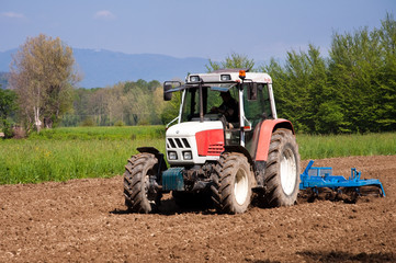 Wall Mural - Red and white tractor with vibrocultor working fields front side