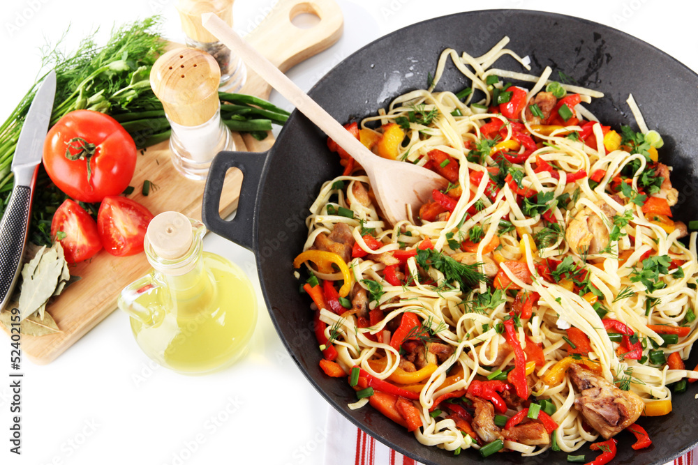 Noodles with vegetables in wok on bright background