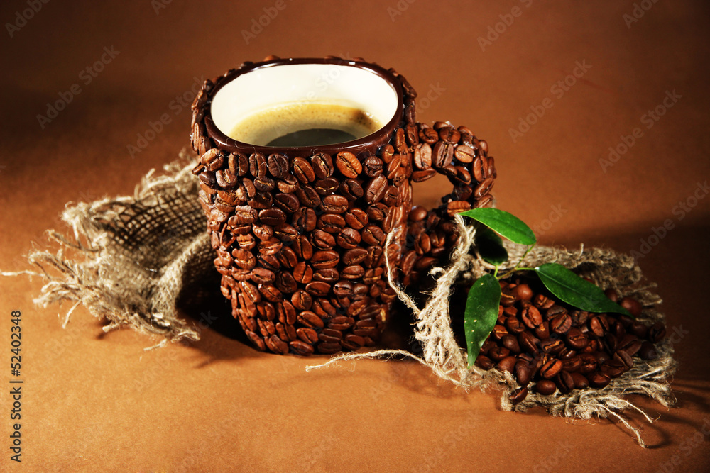 Cup of coffee beans, on brown background
