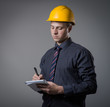 © slasnyi - young builder in a building helmet with a notebook in hands