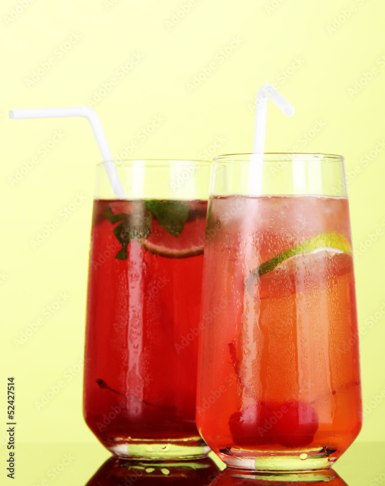 Two cherry cocktails with ice on green background