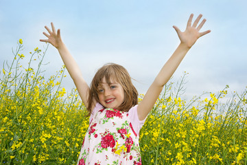 Wall Mural - happy little girl on a field with flowering colza