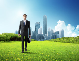 Wall Mural - business man walking on green field and modern city