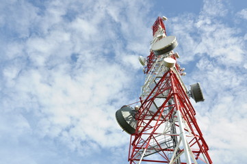 Tower with cell phone antenna system against blue sky