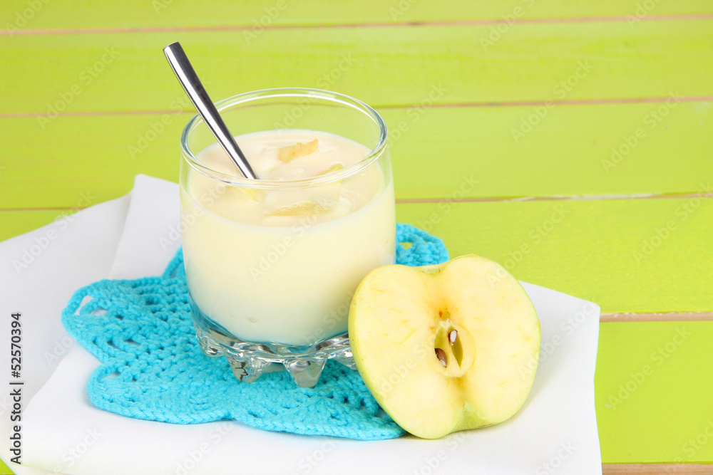 Delicious yogurt in glass with apple on blue tablecloth