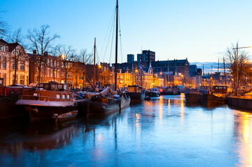 Fototapete - frozen canal with ships in Groningen in dusk