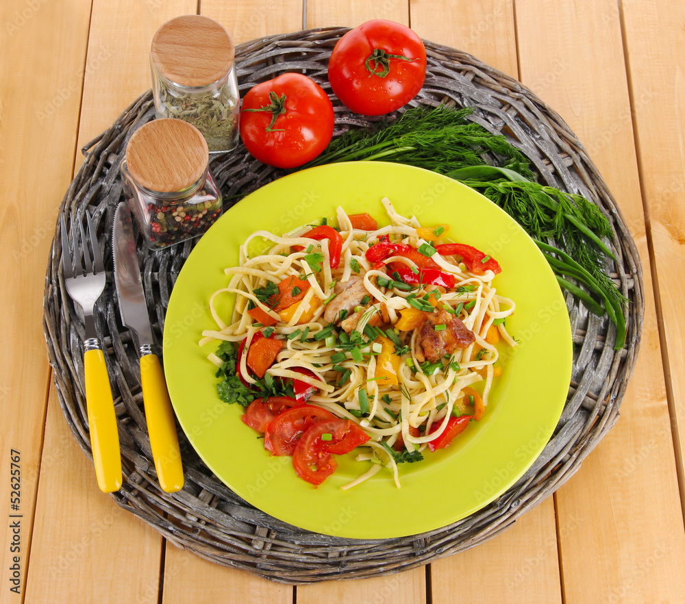 Noodles with vegetables on plates on wooden background