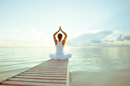caucasian woman practicing yoga at seashore