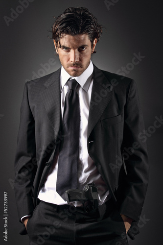 Attractive and elegant man posing with a gun in his trousers Poster
