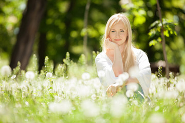 Cute woman rest in the park with dandelions