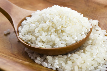 Wall Mural - Rice in wooden spoon on kitchen table