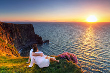 Couple In Hug Watching Sunset On The Edge Of The Cliff.
