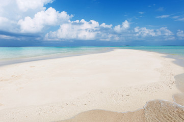 Seascape with white sand on the beach and blue sky with clouds