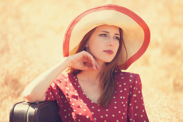 Wall Mural - Redhead girl with suitcase sitting at grass