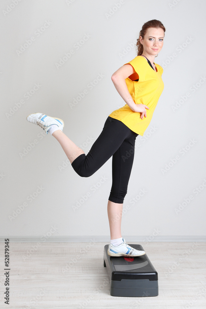 Beautiful young woman exercises on stepper