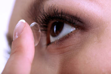 Wall Mural - Young woman putting contact lens in her eye close up