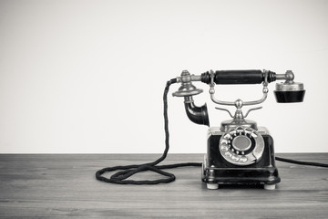 Fototapete - Vintage old telephone on wood table black and white photo