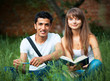 © vladstar - Two students studying in park on grass