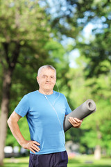 Sticker - Mature man holding an exercising mat in park