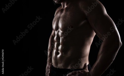 Fotografía Close up of perfect male body isolated on black background
