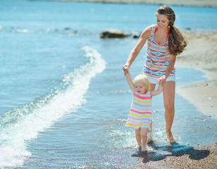 Wall Mural - Mother and baby walking on beach