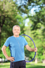 Poster - Fit mature man holding a hulahoop in a park