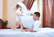 positive father and son having fun at home, pillow fight