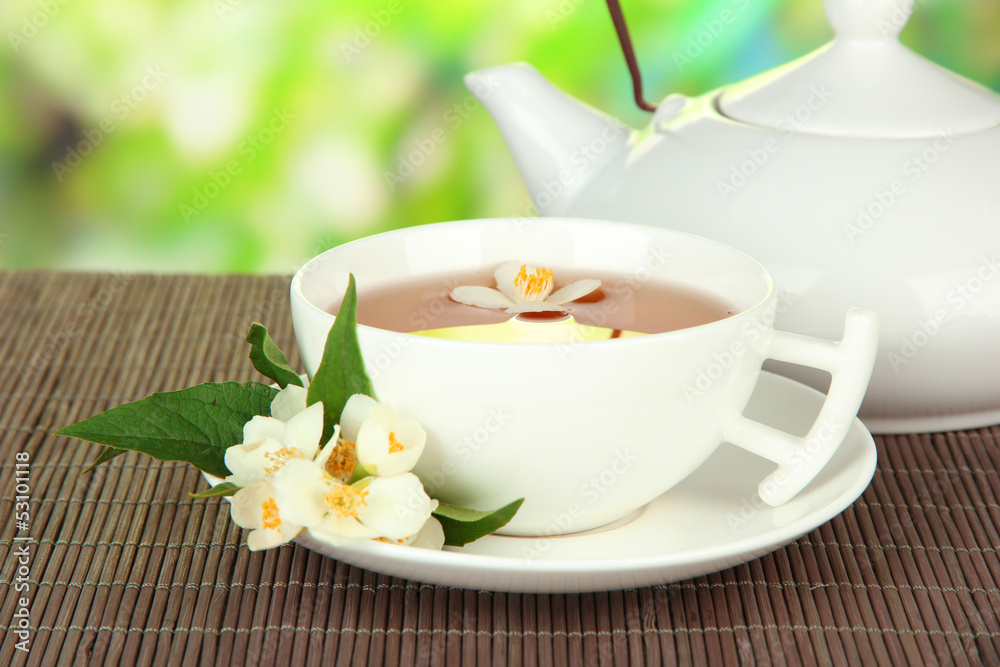 Cup of tea with jasmine, on bamboo mat, on bright background