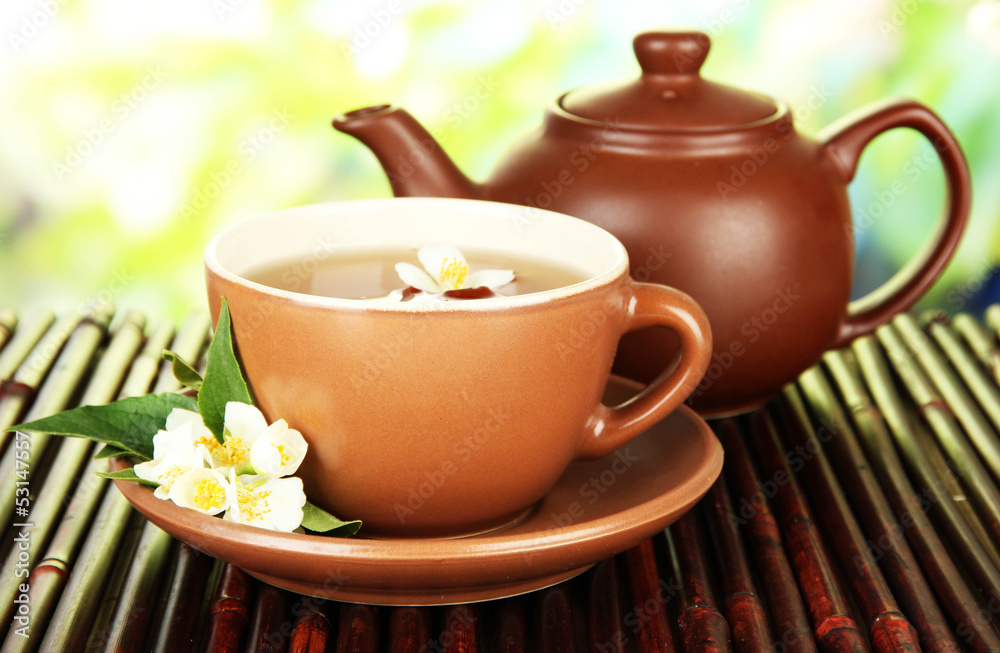 Cup of tea with jasmine, on bamboo mat, on bright background