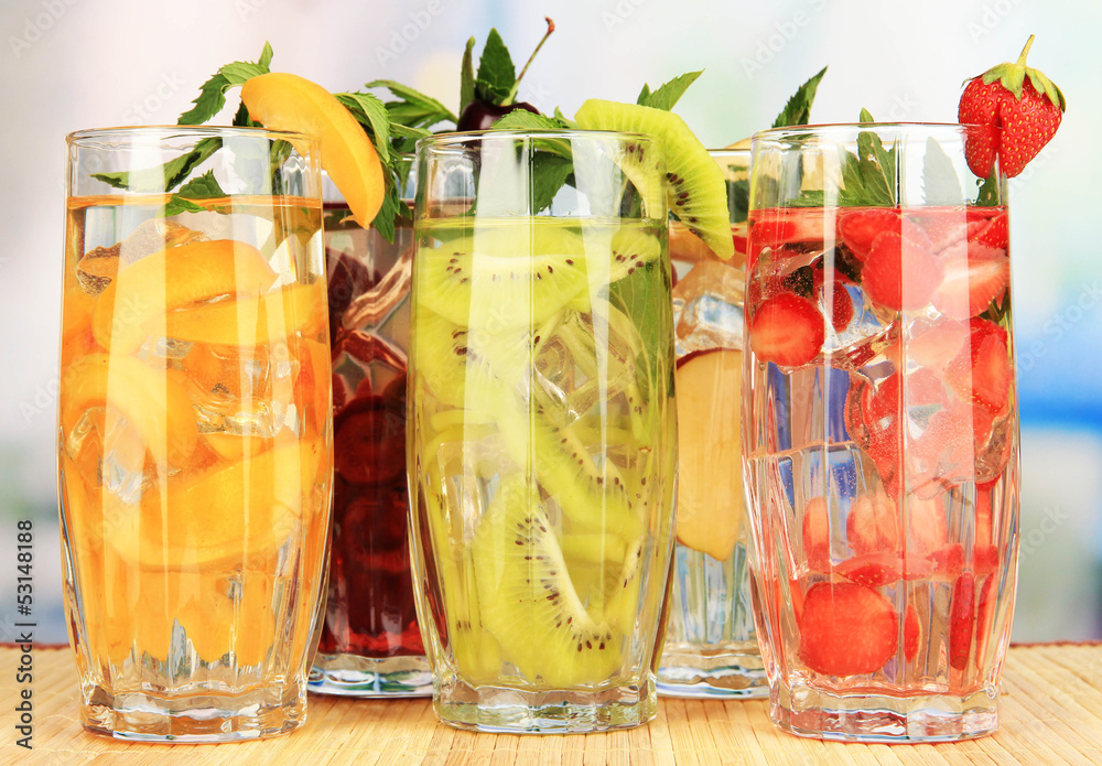 Glasses of fruit drinks with ice cubes on table in cafe