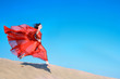 Woman in airy red dress running on sand dunes
