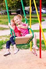 Sticker - Beautiful little girl on a swings outdoor in the playground