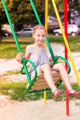 Sticker - Beautiful little girl on a swings outdoor in the playground