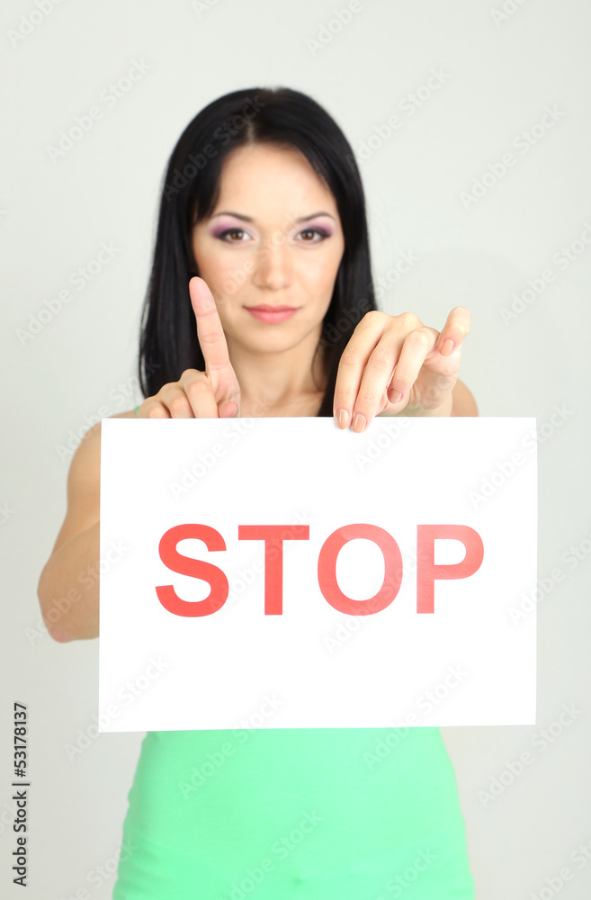 Girl showing stop sign on grey background