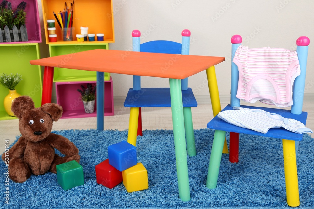 Small and colorful table and chairs with baby clothes