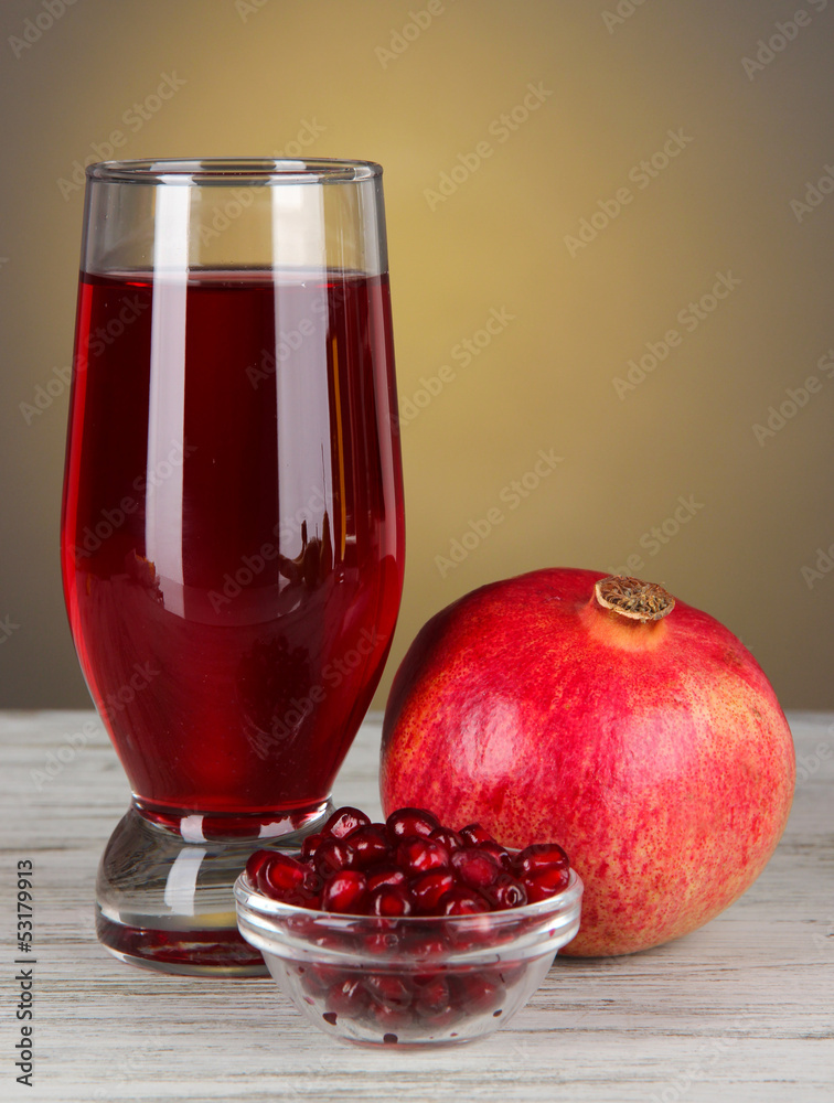 Glass of fresh garnet juice on table on gray background