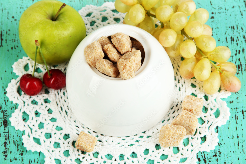 Unrefined sugar in white sugar bowl on wooden background